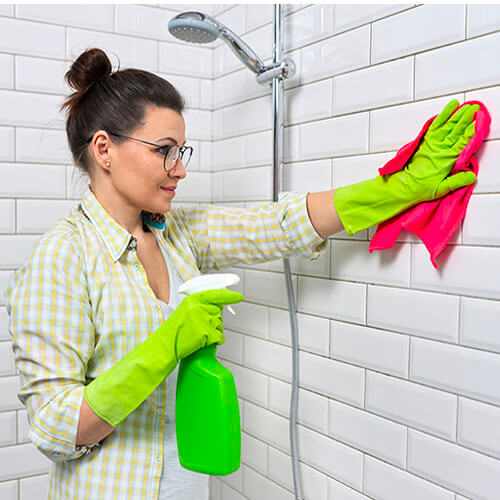 a woman cleaning bathroom tiles